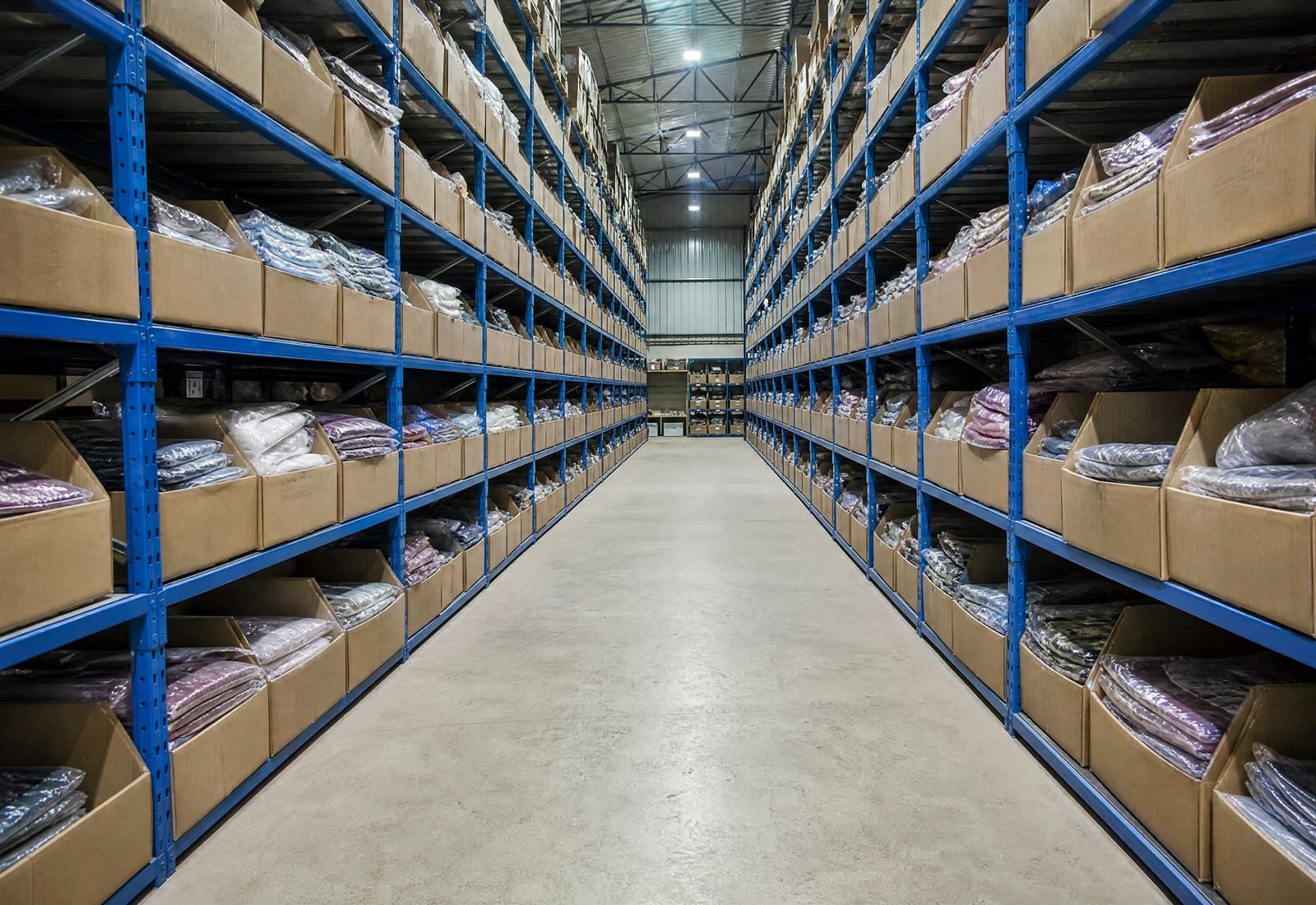 A finished goods warehouse aisle with racked, polybagged garments