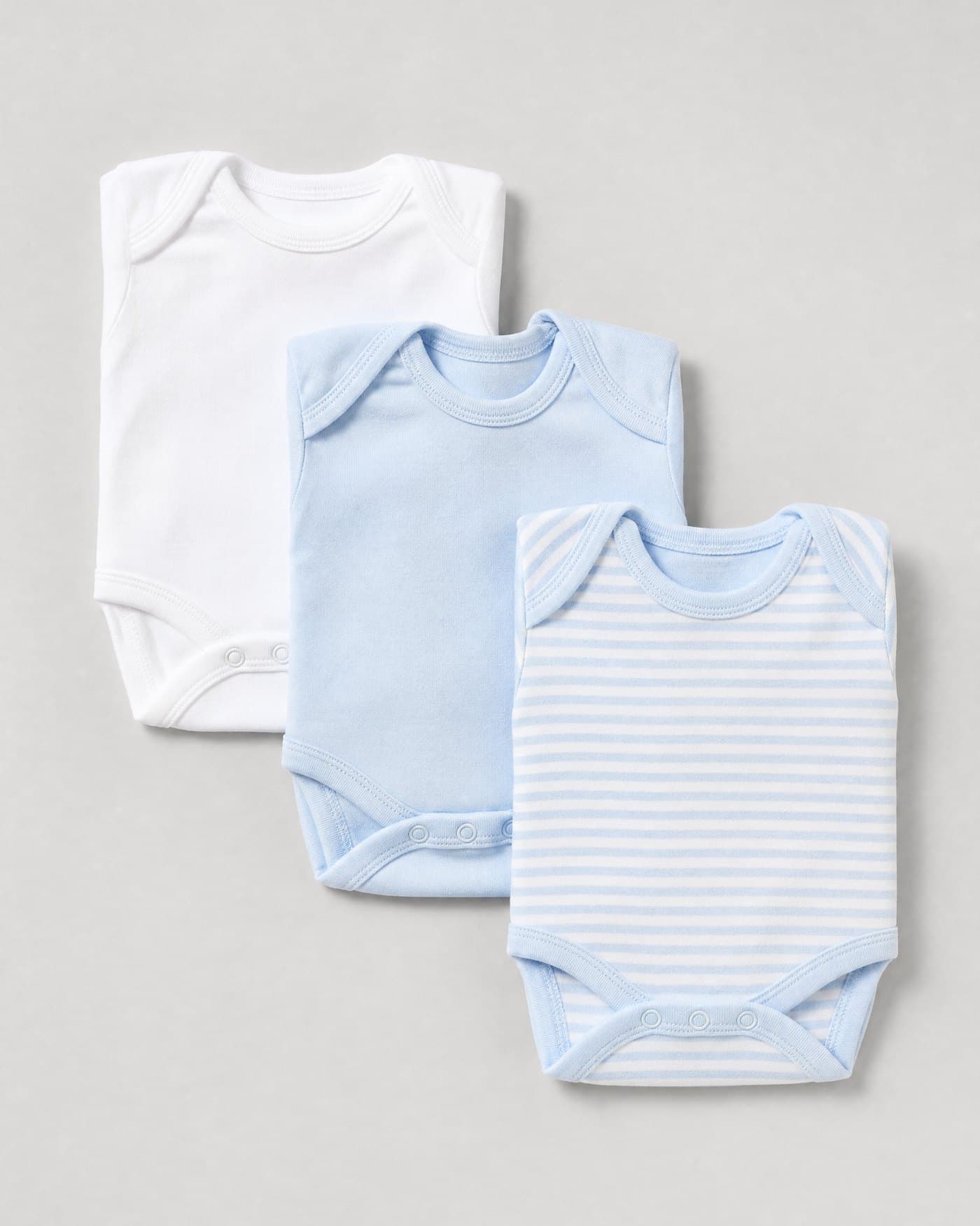 Folded infant bodysuits in white and pale blue cotton jersey