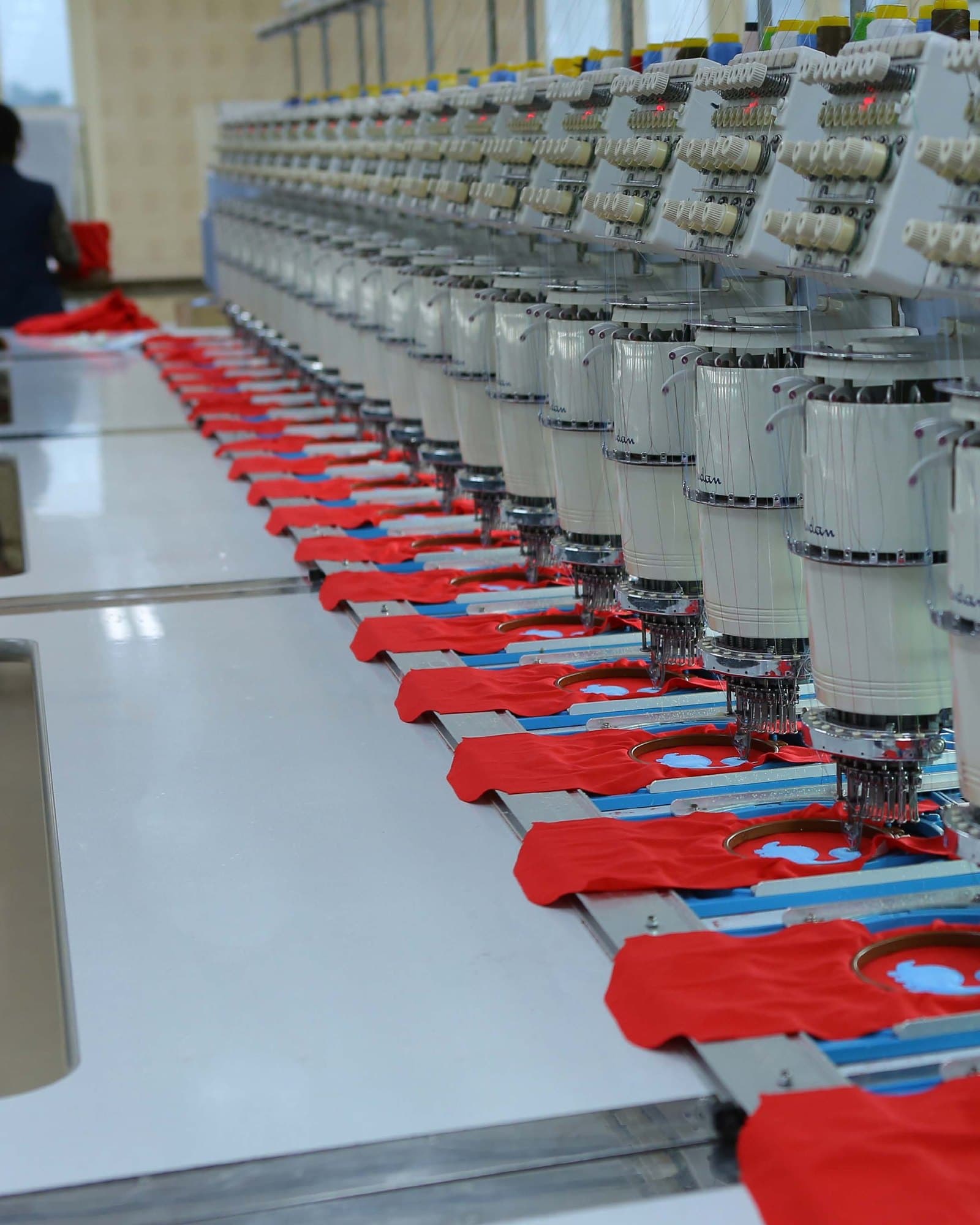 A machine hall with knitted garments staged at each machine head